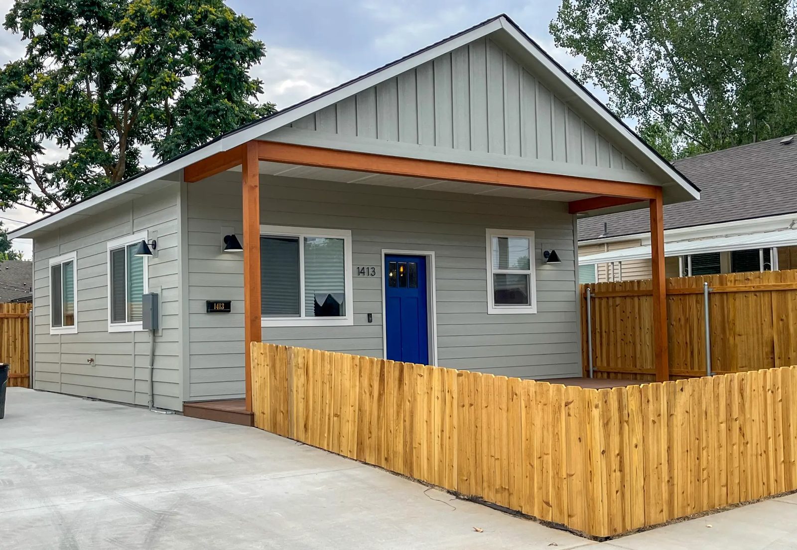 Sage green ADU with covered porch and cedar fence built by DSC