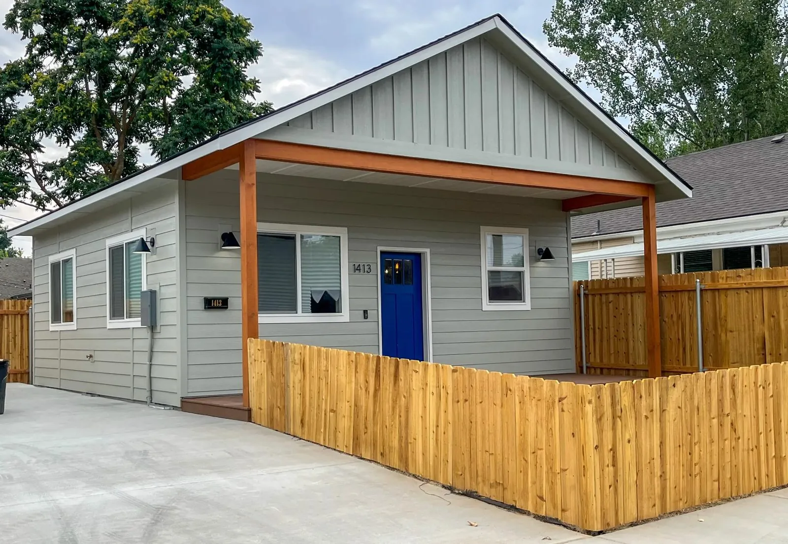 Sage green ADU with covered porch and cedar fence built by DSC