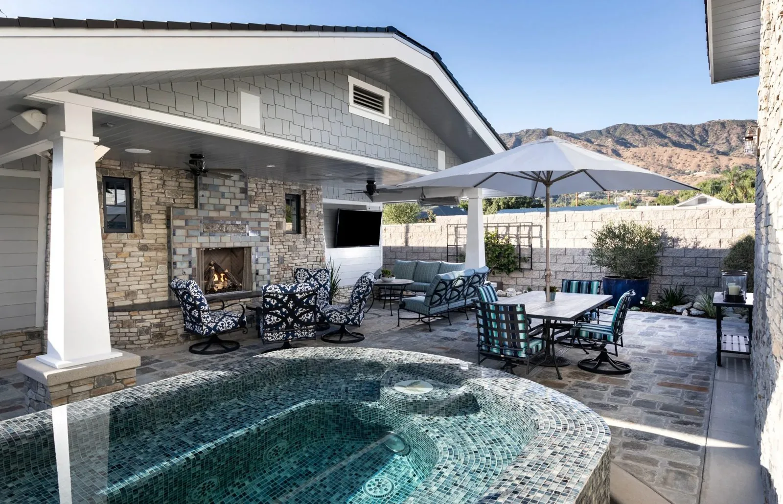 Outdoor living space with pool, covered patio and stone fireplace from the DSC portfolio