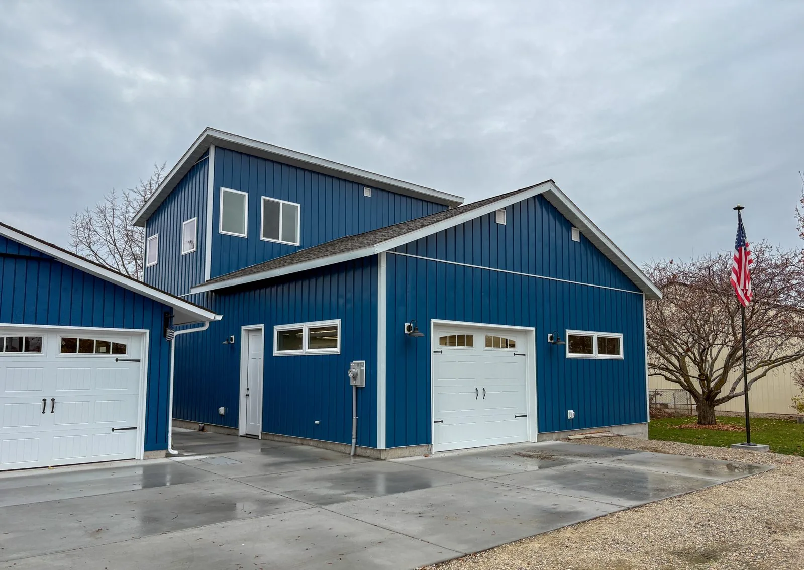 Blue two-story woodshop building with white garage doors in Emmett